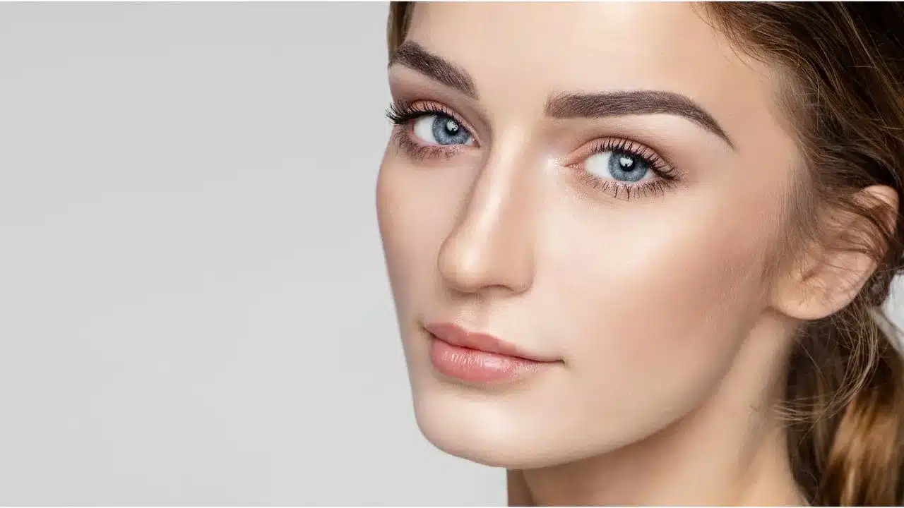 Surgeon marking woman's face for cosmetic procedure planning.