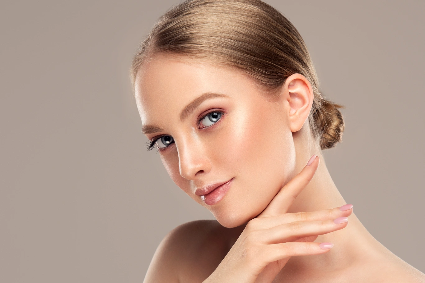 ponytail facelift Baltimore facial rejuvenation results young woman with a sleek low bun gently touching her jawline demonstrating a ponytail facelift